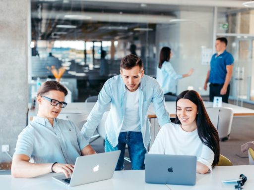a group of people sitting around a table with laptops