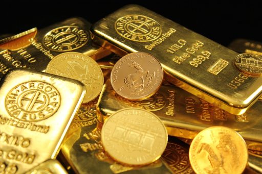 Gouden beleggingsmunten en een goudstaaf op een houten ondergrond