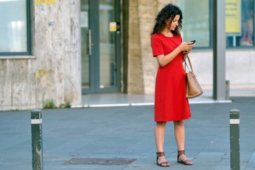 Een jonge persoon kijkt bezorgd naar een smartphone met financiële grafieken