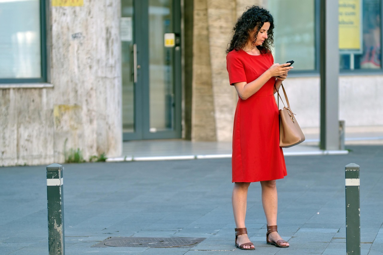Een jonge persoon kijkt bezorgd naar een smartphone met financiële grafieken
