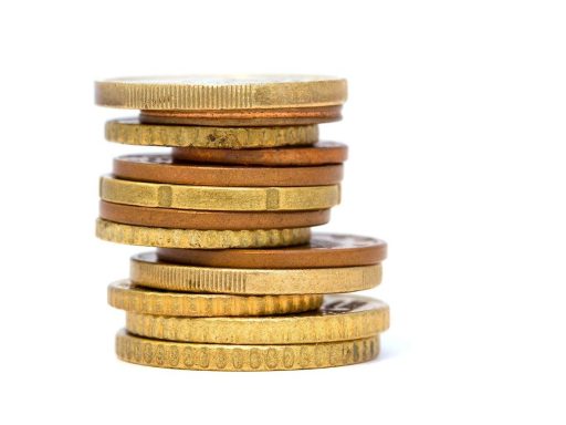 Goudstaven en gouden munten op een houten tafel, symboliserend voor goudverkoop en belastingregels in België