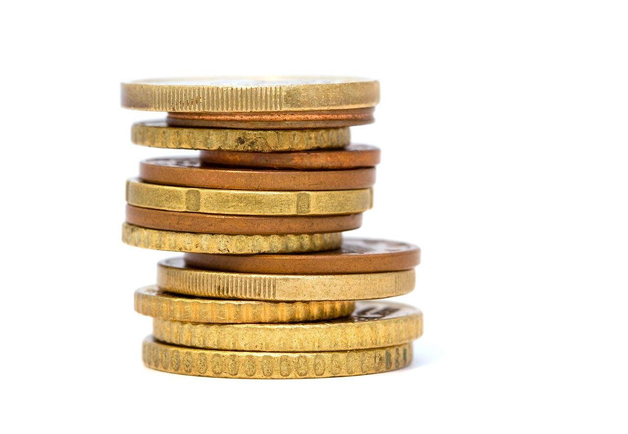 Goudstaven en gouden munten op een houten tafel, symboliserend voor goudverkoop en belastingregels in België